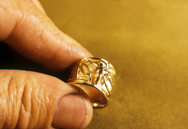 Toza holding gold ring with relief design, 1960s